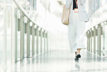 Fototapeta premium ガラスの通路を歩く30代ビジネス女性