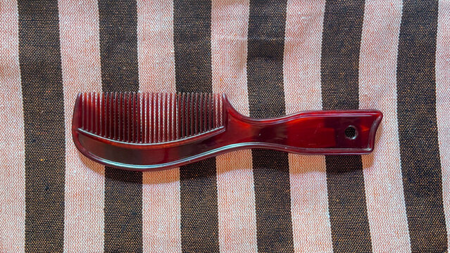 Brown tortoise shell hair comb on striped beige and black fabric