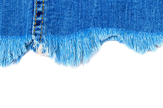 Denim fabric with frayed hem showing details of construction and texture in the textile industry