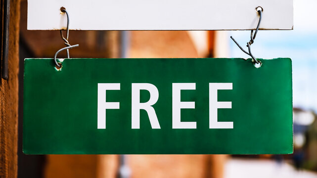 Sign shows free items available outside a shop during the day in a busy street area