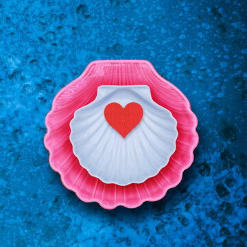 Colorful shell with red heart decoration placed on blue surface in warm daylight