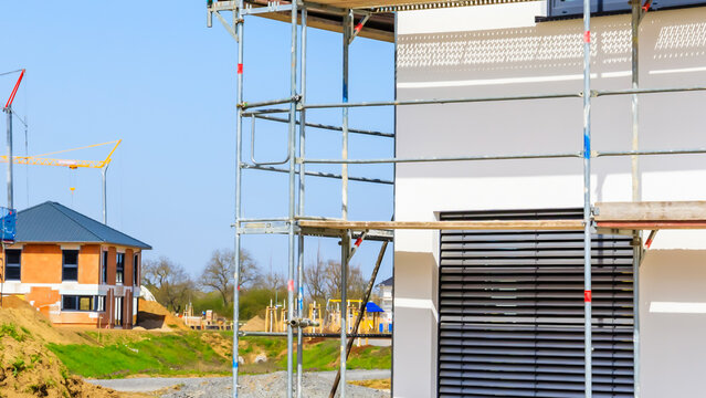 Construction site shows scaffolding around a building under development in a clear blue sky in a residential area