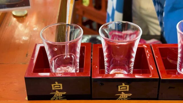Pouring sake into traditional masu cups at a tasting event.