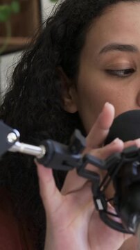 Vertical video: Preparing to record podcaster in rust top adjusting mic pop filter at home studio