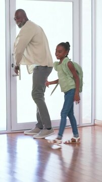 Dad kneeling, opening glass door, guiding girl home, girl taking mint-green backpack to counter