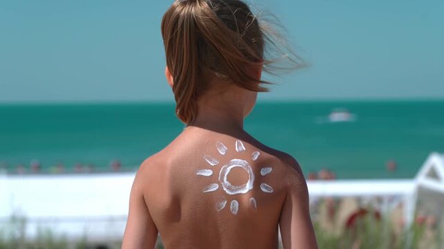 Little child with sunscreen or sunblock on background of beach with blue sea. Skin care from sun. Summer vacation travel holiday