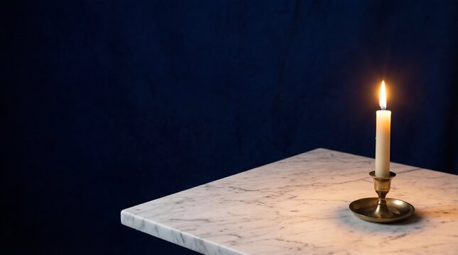Single burning candle in brass holder on marble table against blue background