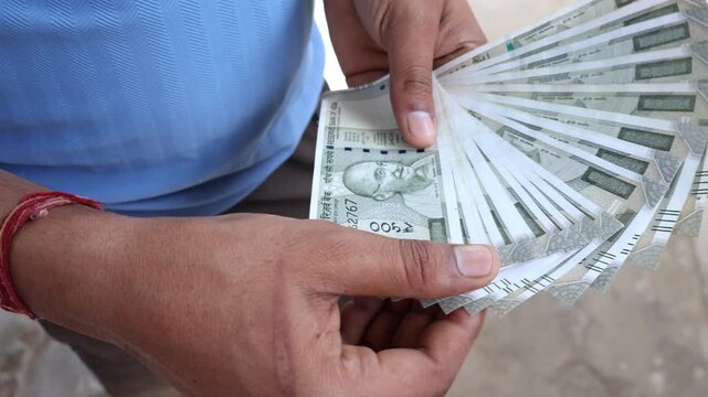 Man counting 500 rupees indian currency notes.