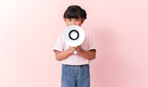 excited young southeast asian girl in pink shirt shouting into megaphone on isolated pink background, energetic promotion and announcement concept
