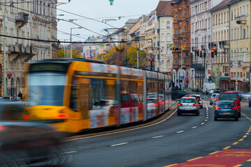 Fototapeta premium Fast moving yellow tram on a wide Budapest street with cars and old buildings