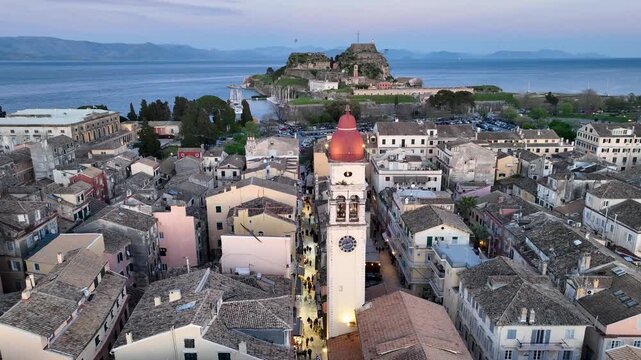 Drone view of Saint Spyridon church red dome and historic Corfu town streets at twilight, with the Old Fortress, Greece