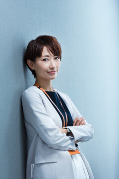 オフィスの壁に寄りかかる30代ビジネス女性