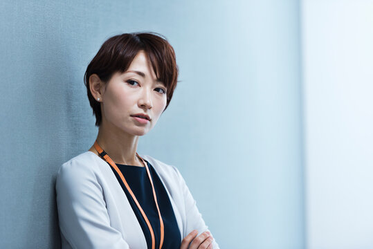 オフィスの壁に寄りかかる30代ビジネス女性