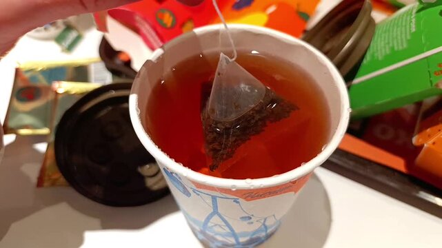 The process of brewing tea with a pyramid-shaped tea bag in a paper cup at a fast food restaurant