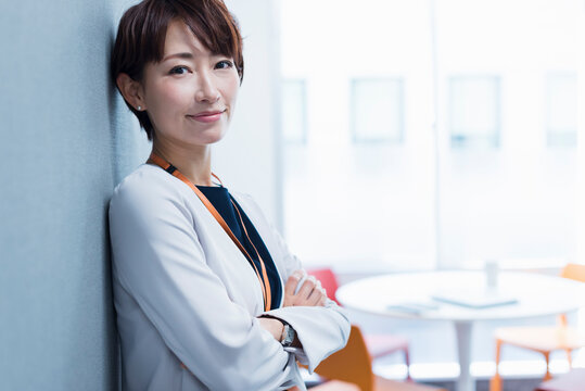 オフィスの壁に寄りかかる30代ビジネス女性