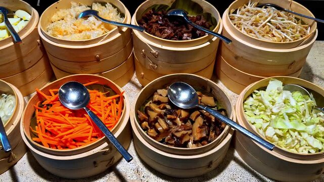 Buffet condiment station with bamboo bowls of sliced eggs, onions, carrots, mushrooms, bean sprouts, and cabbage, arranged for noodle or rice meal customization.