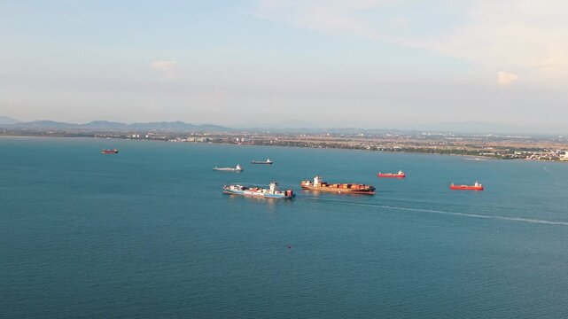 Push in drone shot of container ships in the Strait of Malacca near Penang, Malaysia, showing maritime traffic, cargo transport, and global shipping routes across the open sea. UHD.