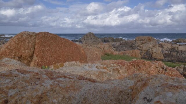 A scenic view of a rocky shore with breaking ocean waves under a dynamic sky filled with clouds at Ramsgate, South Coast, KwaZulu-Natal.