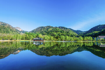 Obraz premium 新緑の湯ノ湖と水鏡のような水面に映った金精山と山並