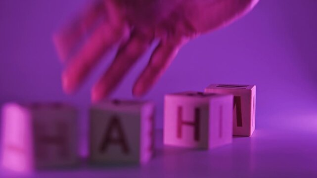 A hand hits wooden blocks with the word PAIN. Close-up of the hand aggressively destroying the word.