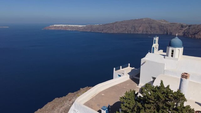 Santorini landscape with the deep blue Aegean Sea revealing a white chapel and Oia on the horizon, capturing iconic island architecture and dramatic caldera scenery.