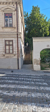 A narrow passage with steep stairs called Kapucinske stube in the historic Upper Town of Zagreb featuring old buildings and a lush tree