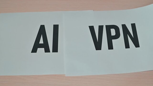 A hand moves paper sheets with the letters AI and VPN printed on them. This action illustrates the integration of artificial intelligence and virtual private networks for improved online privacy