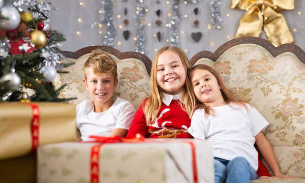 Two girls and boy on sofa in Christmas interior