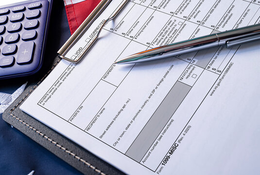 Tax form 1099-MISC with calculator and pen on clipboard flat lay concept of financial accounting filing