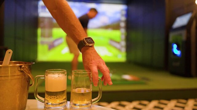 Caucasian Man Playing Indoor Golf Simulator at Sports Bar with Beer