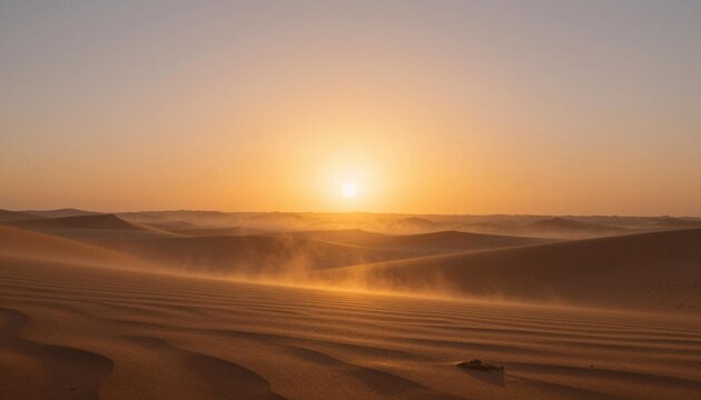 Golden desert sunrise over rippled sand dunes with drifting sand and a warm glowing sky