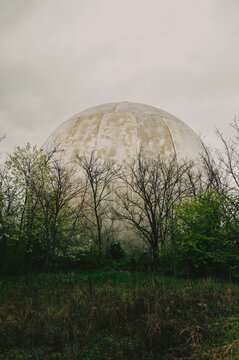Weathered Radome Rising Behind Bare Trees, Mistladen Meadow Foreground, Cracked Concrete Base, Moss And Lichen