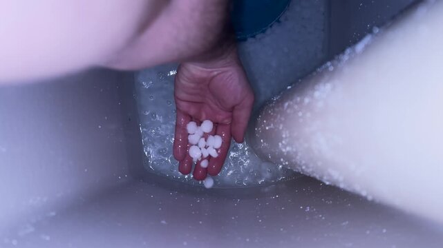 Close-up of hand adding salt into a water softener tank, showing maintenance, descaling process, and water treatment system.
