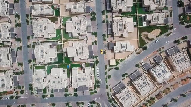 Top down drone rising over geometric neighborhood with yellow car in Dubai