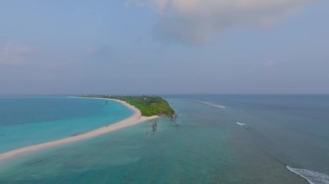 Beautiful aerial drone footage flying along the southern coastline of Vashafaru Island over dense tropical jungle and stunning turquoise blue waters in northern Maldives.