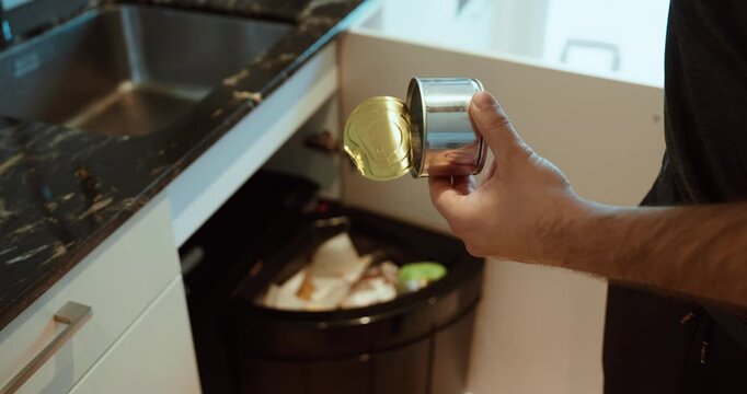 Man throwing a metal can into regular trash instead of recycling, representing waste, environmental impact, and incorrect disposal.