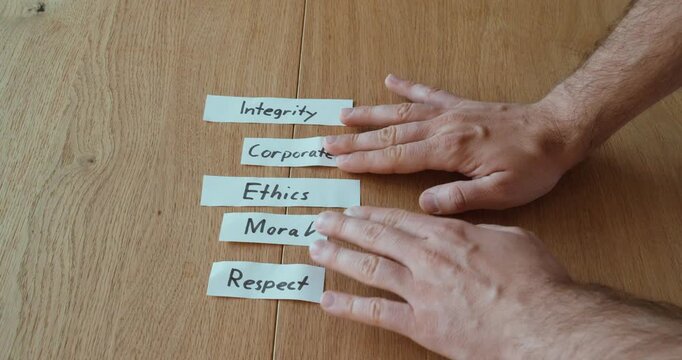 Hands arranging words like integrity, ethics, corporate, moral, and respect, representing prioritization of values and decision-making.