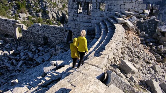 Young travelers discover ancient amphitheater and ruins of Termessos. Walking, climbing, enjoying view and ancient history in warm Turkish light.