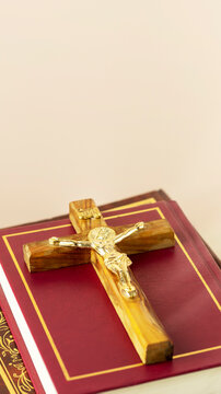 Wooden Cross on Red Bible Book Close Up on Neutral Background with Copy Space, for Christian Faith Content, Prayer Themes, Church Materials, Religious Holidays, and Spiritual Reflection Concepts