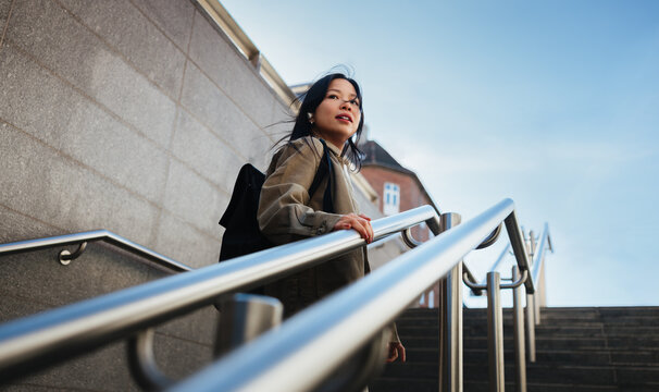 Young woman ascending city stairs in a rush with hopeful expression
