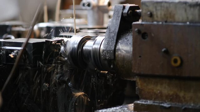 A focused shot of a mechanical component being shaped by a machine tool while industrial lubricant flows over the metal surface.