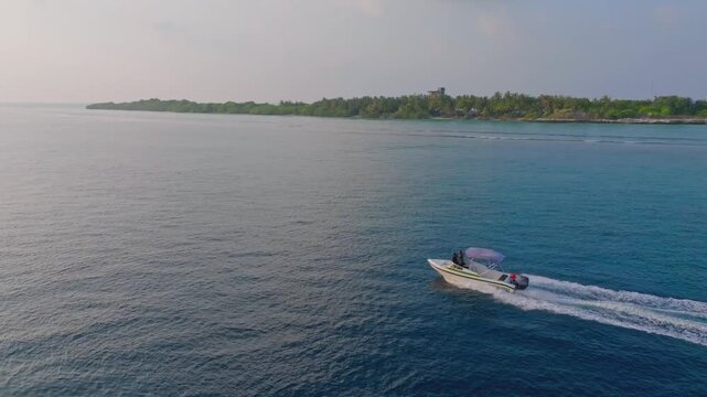 Dynamic aerial drone footage chasing a traditional local fishing boat near Vashafaru Island in northern Maldives as it travels across the clear blue tropical waters.