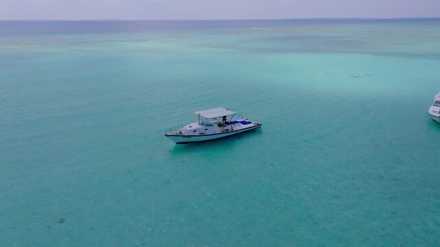 Cinematic aerial drone footage orbiting around a dive boat anchored near a beautiful sandbank in the open ocean close to Vashafaru Island in northern Maldives.