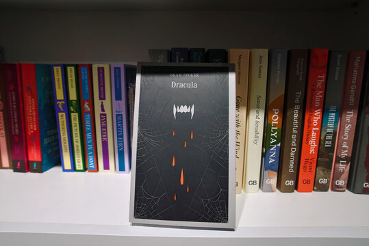 Minsk, Belarus. Apr 12, 2026. Black book cover for Bram Stoker's Dracula with fangs and blood drops illustration in retail bookstore or public library with various classic novels on the shelf backdrop
