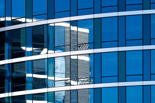 Modern blue glass building architecture facade with windows pattern and abstract reflection creating a clean urban background texture
