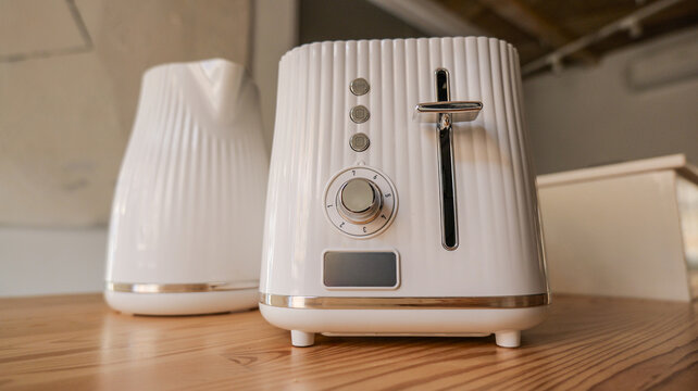 Modern white kitchen appliances including a toaster and kettle on a wooden countertop