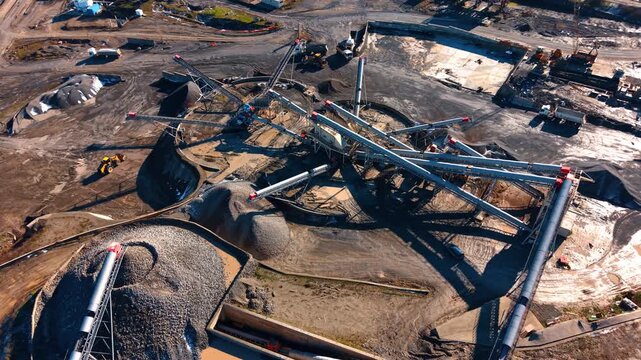Construction site with machinery. Machines work on a construction site with gravel piles and equipment visible around the area under bright sunlight.