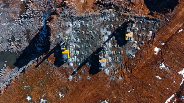 Drilling machines at construction. Workers operate drilling machines on a construction site during daylight. The ground shows signs of recent excavation.