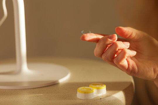 Hand holding contact lens for vision correction with lens case for eye care routine