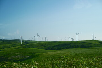 Wind turbines on green rolling hills under blue sky in Hokkaido Japan © Otsuka Yamato